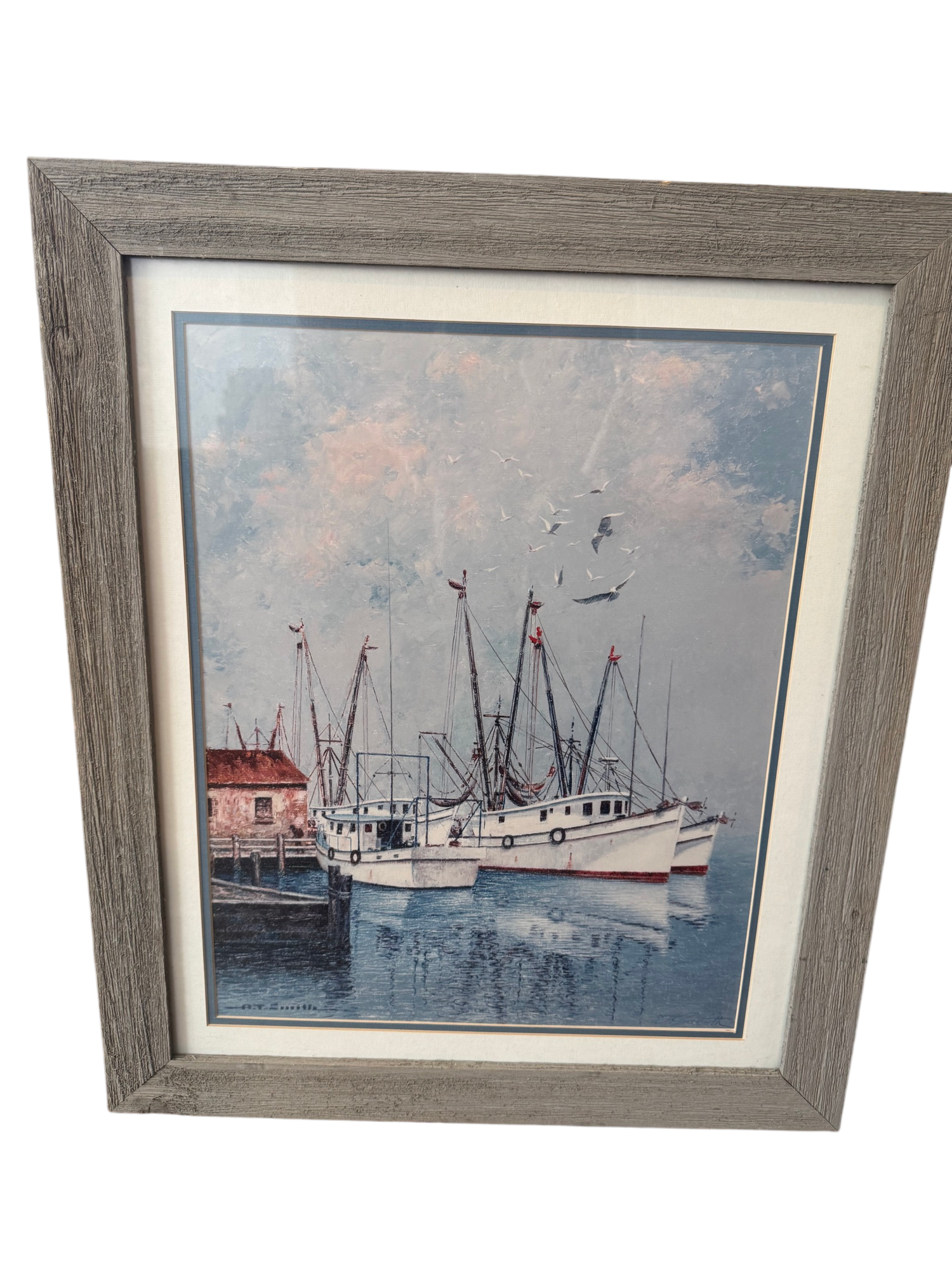 Framed print of shrimp boats docked at harbor with red-roofed building, gray wood frame with cream matting
