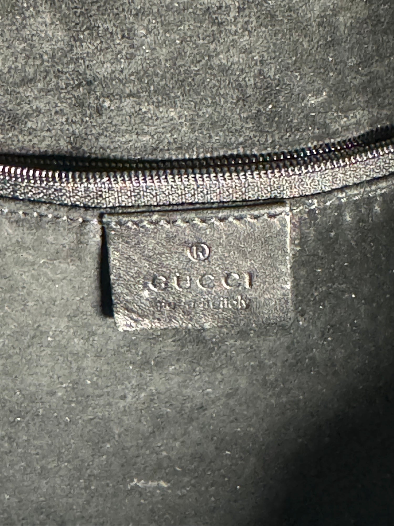 Close-up of interior label reading 'GUCCI' with additional text below, metal zipper visible