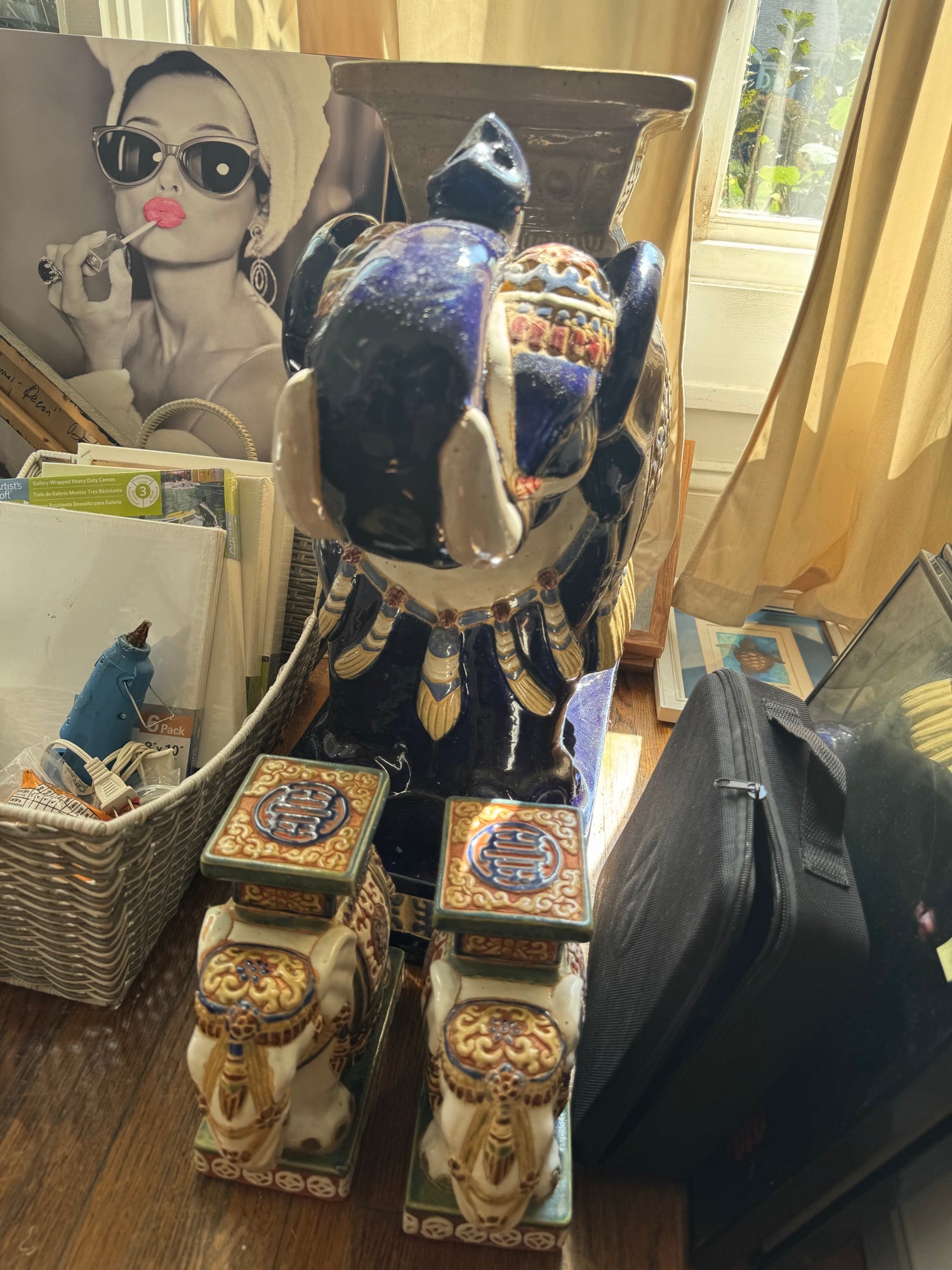Full view of large cobalt elephant garden stool with gilt accents, cream elephant stools displayed in front, interior setting