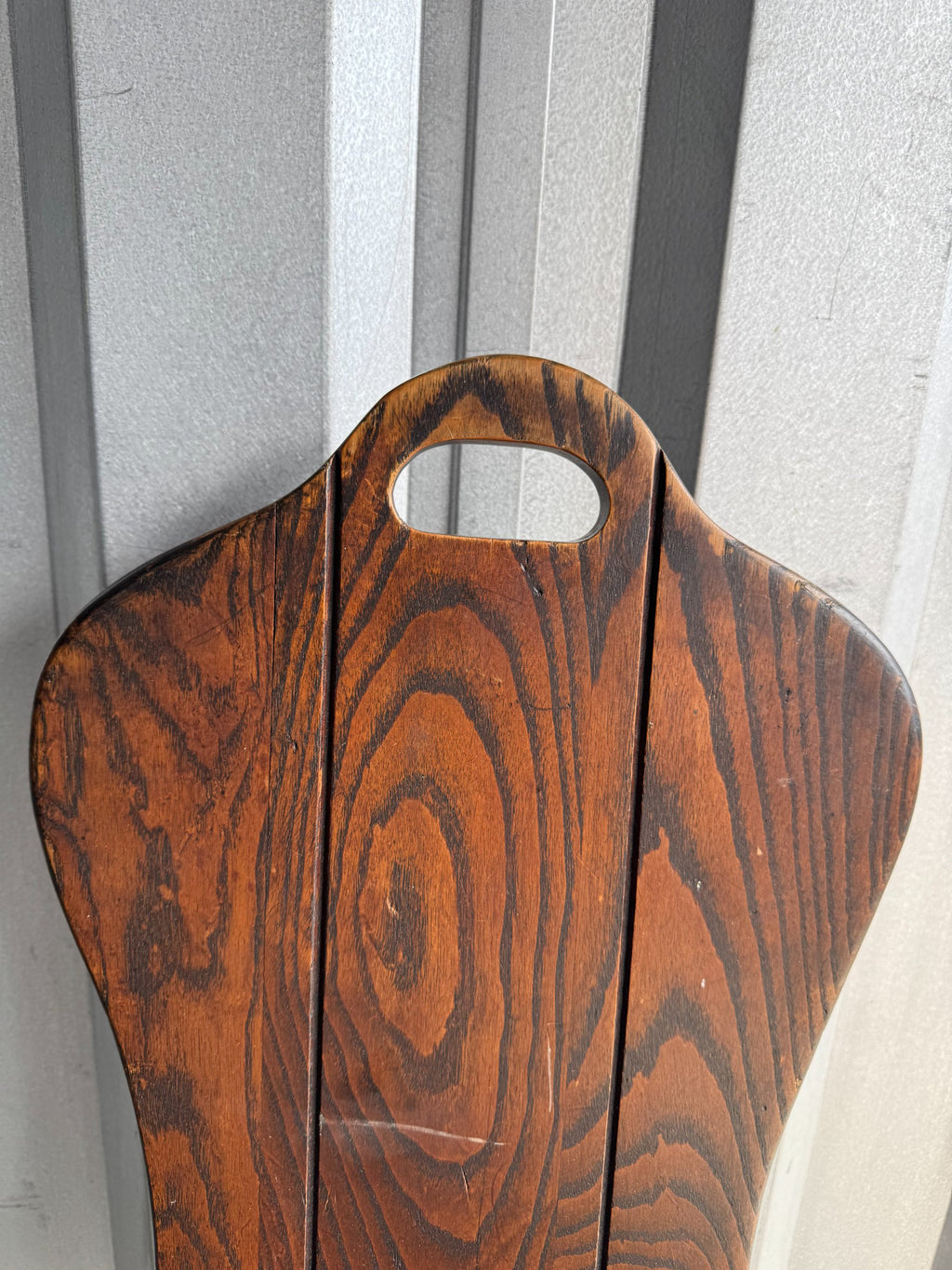 Close-up of backrest handle cutout and wood grain pattern in reddish-brown oak