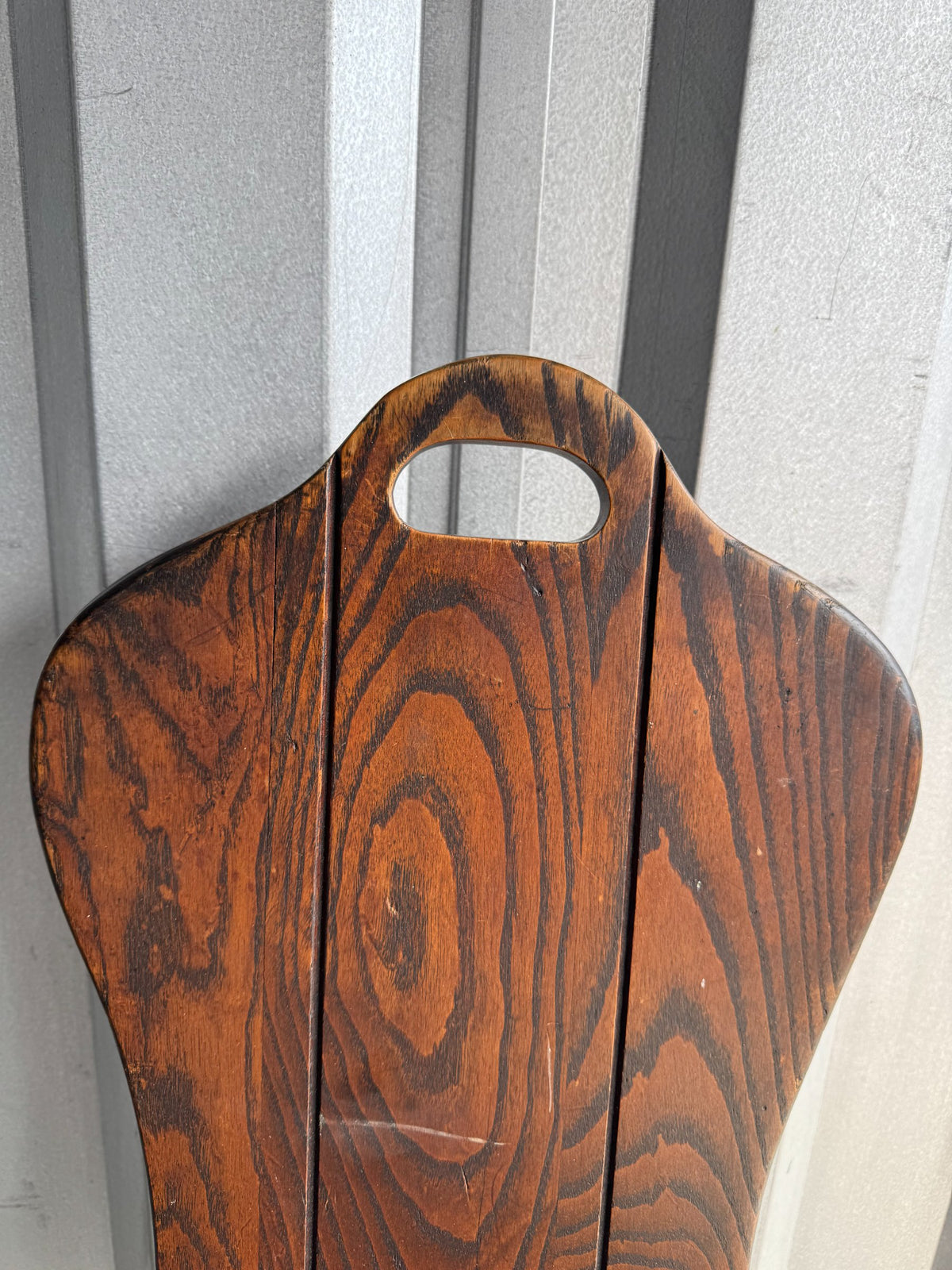 Close-up of backrest handle cutout and wood grain pattern in reddish-brown oak