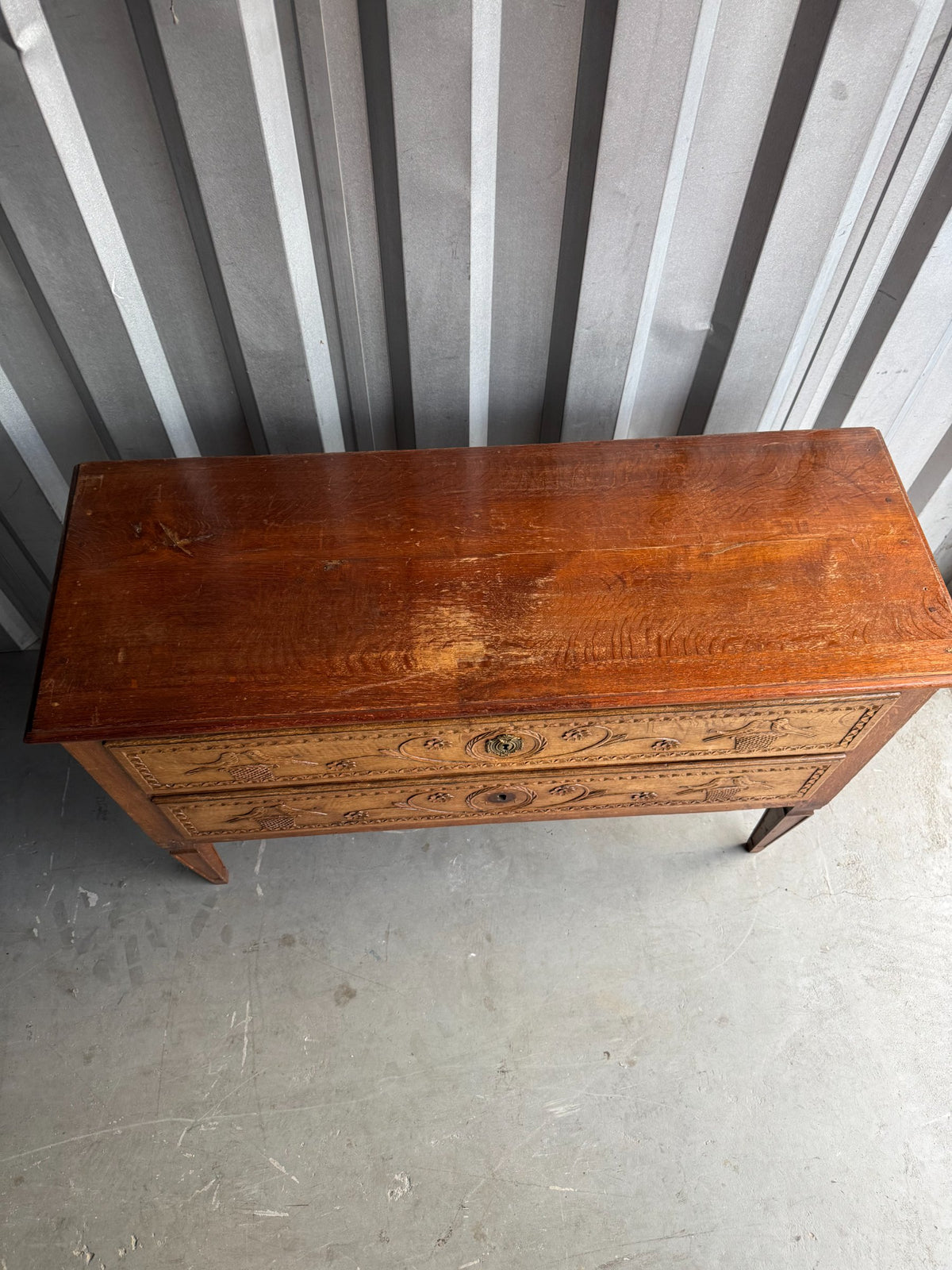 Front view at angle emphasizing carved bird and floral motifs on both drawers