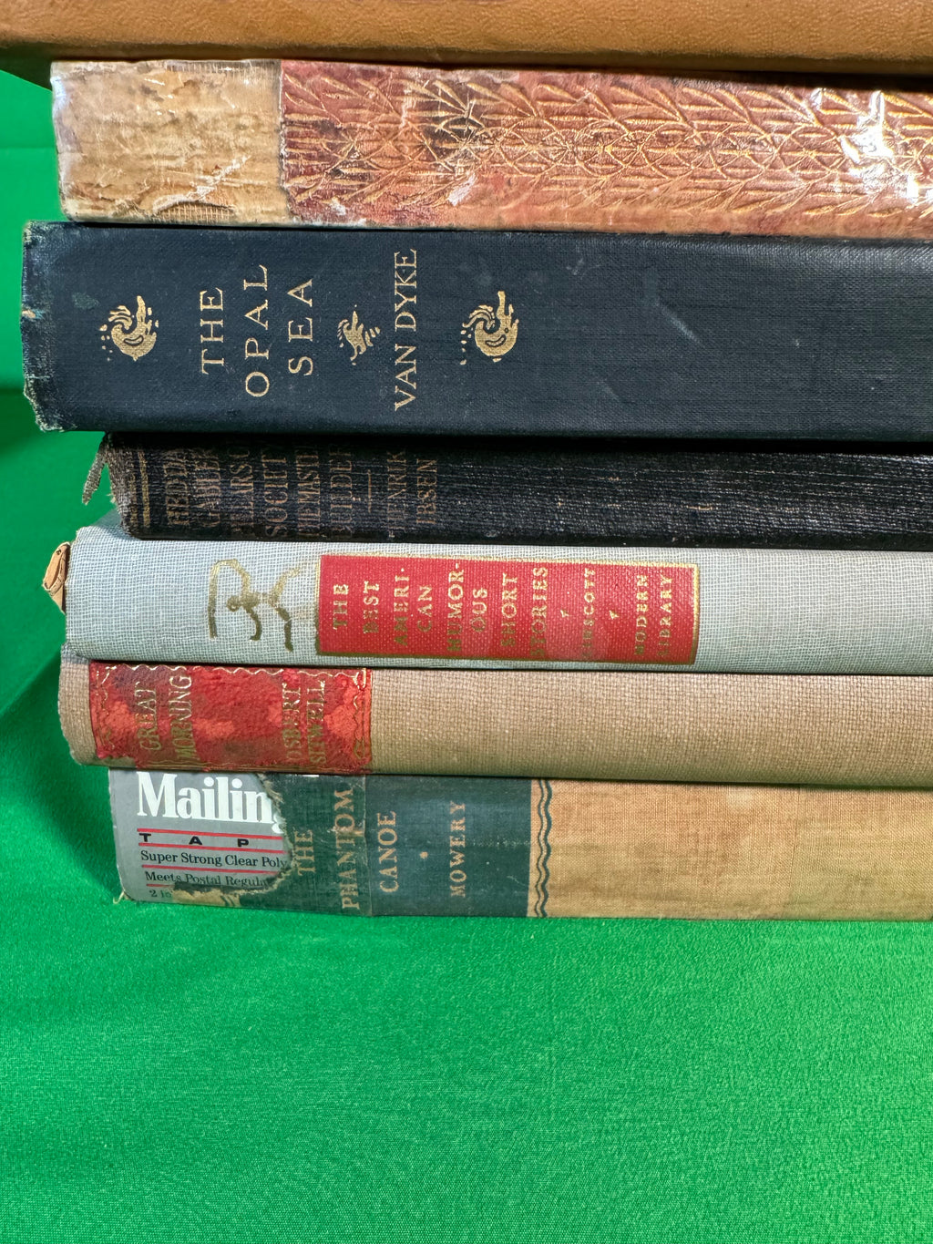 Closer view of the bottom of a stack of vintage hardcovers: The Opal Sea, a Modern Library Ibsen, The Best American Humorous Short Stories, Great Morning by Osbert Sitwell and The Phantom Canoe