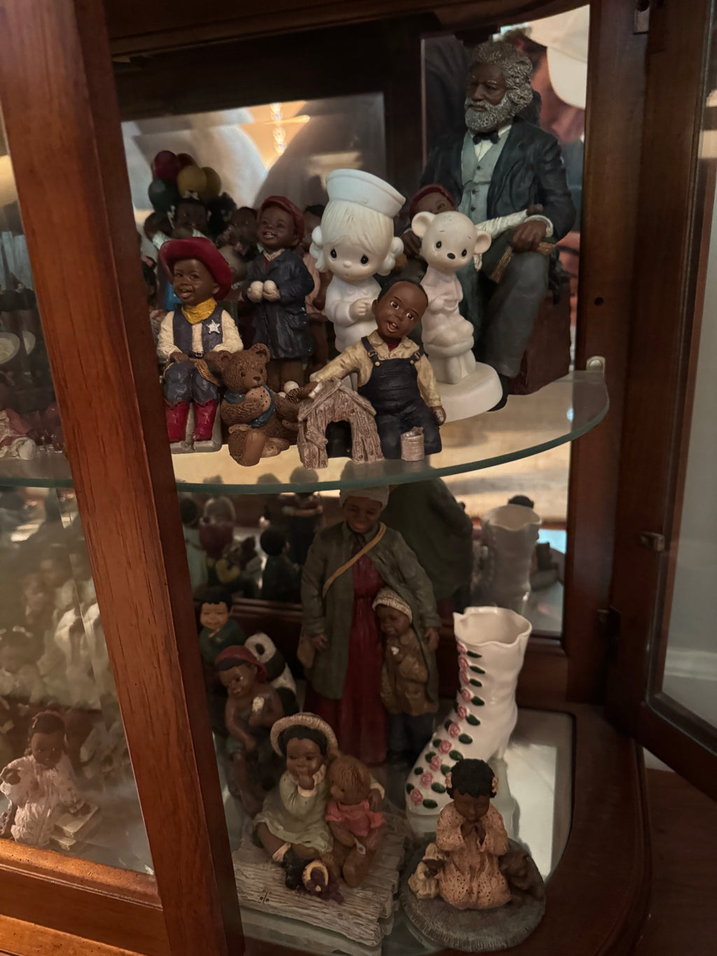 Shelf of All God's Children figurines including cowboy and snowball figures, a Precious Moments nurse figure, and a seated bearded man figurine