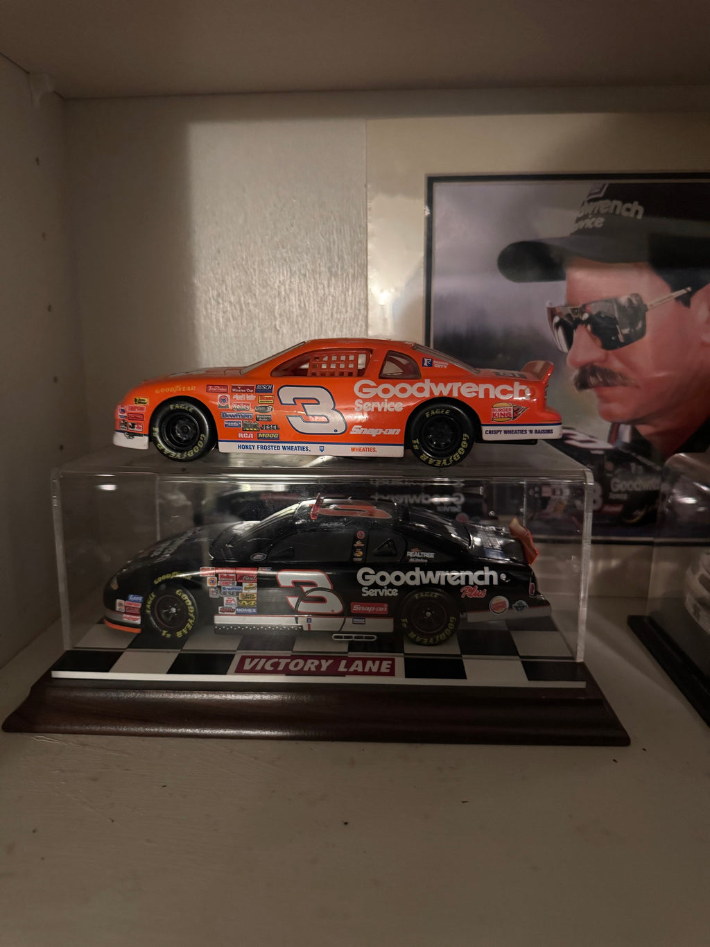 Orange Wheaties Goodwrench #3 car above the black Goodwrench Plus #3 car in a Victory Lane display case