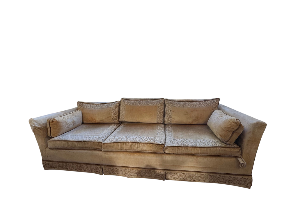 Gold velvet three-cushion sofa seen from the front in a bright room