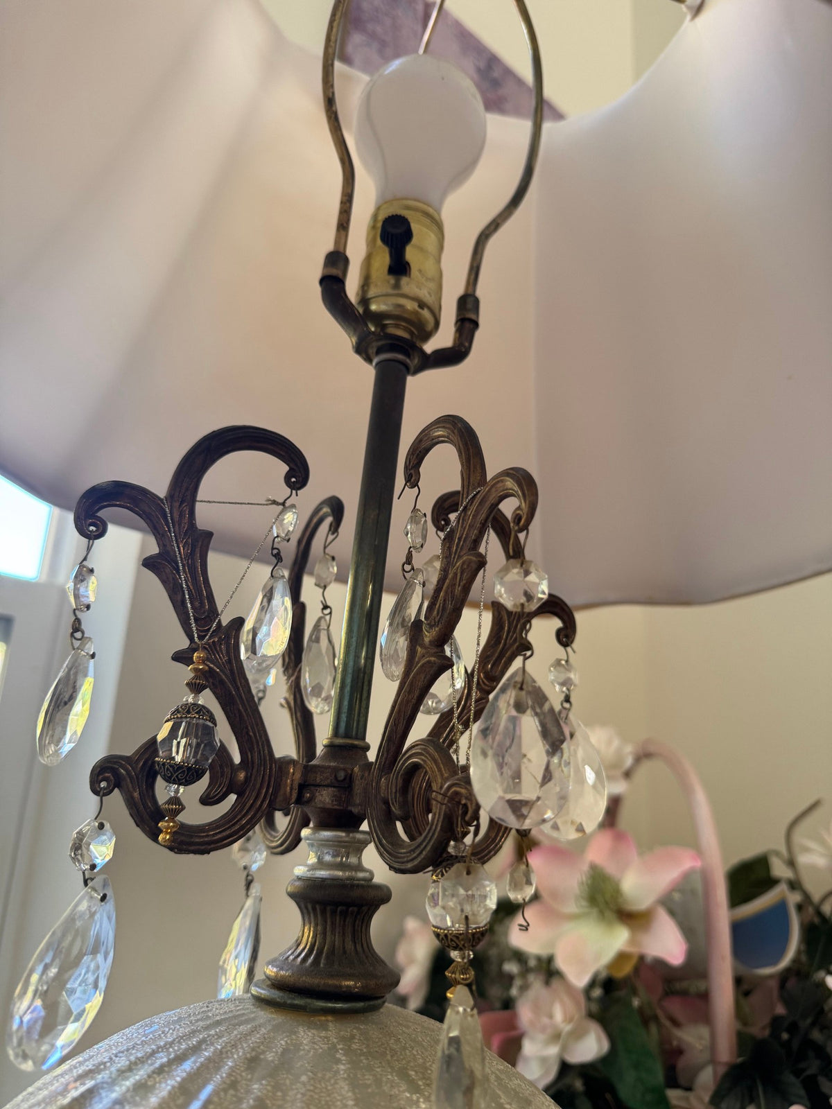 Scrolled metal crown with hanging crystal-style drops under the shade