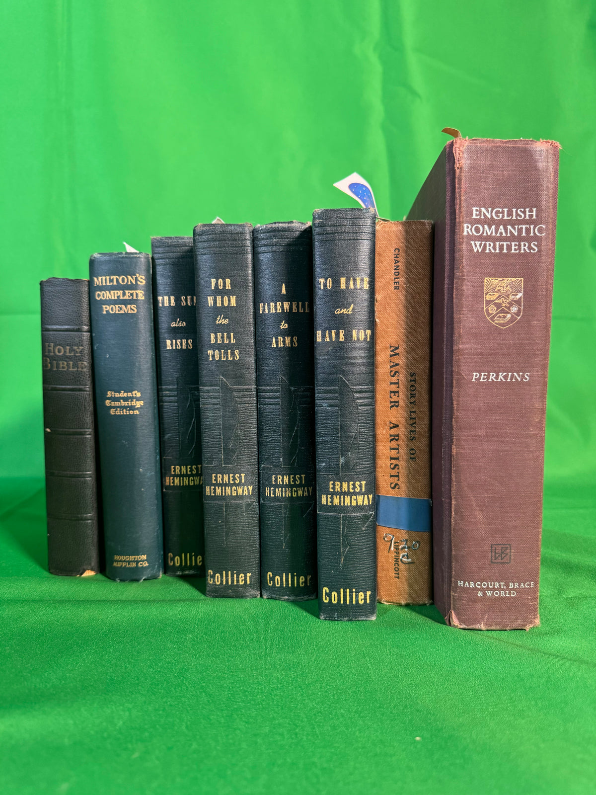 Four matching Collier editions of Ernest Hemingway — The Sun Also Rises, For Whom the Bell Tolls, A Farewell to Arms and To Have and Have Not — stood on green cloth beside Milton's Complete Poems and English Romantic Writers