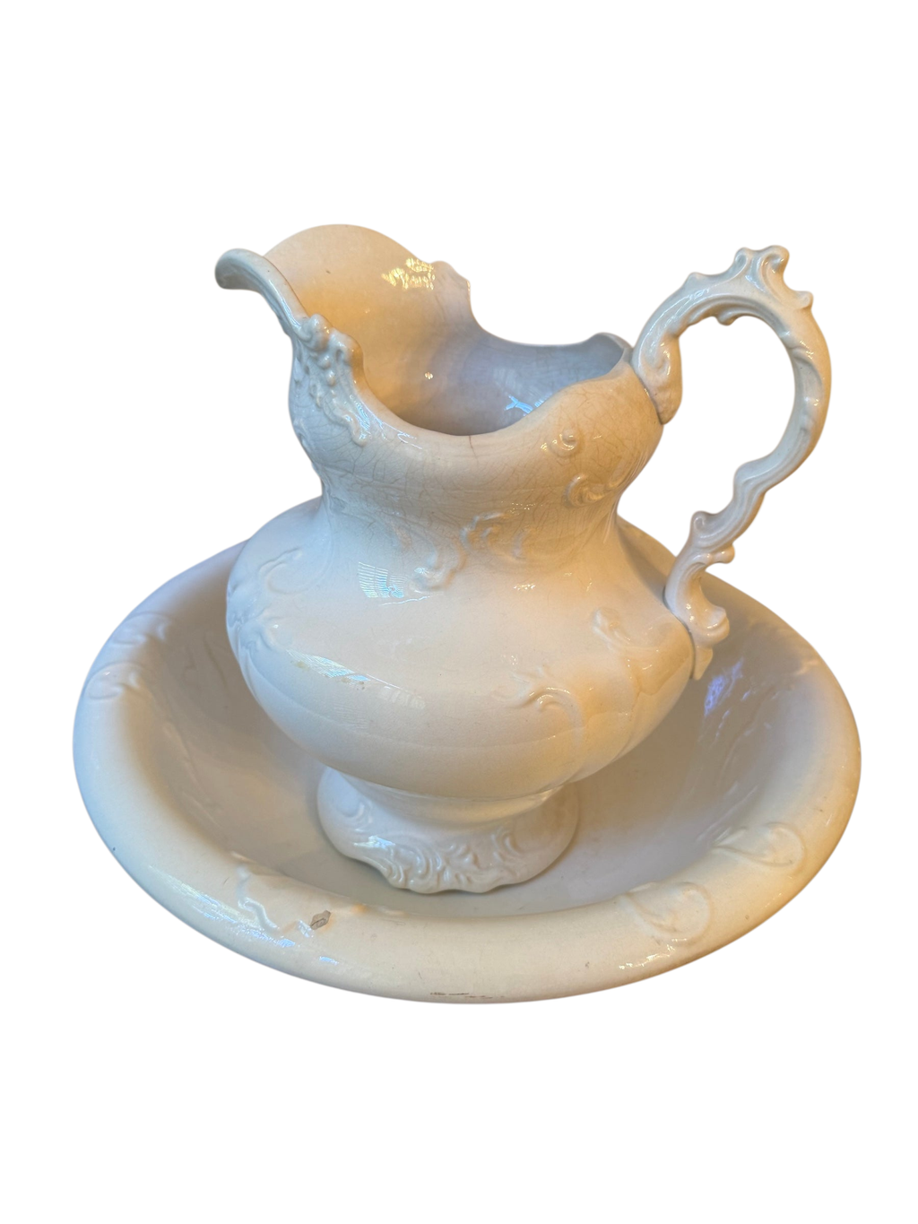White ironstone pitcher with scroll handle set inside a matching scalloped wash bowl