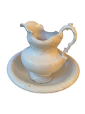 White ironstone pitcher with scroll handle set inside a matching scalloped wash bowl