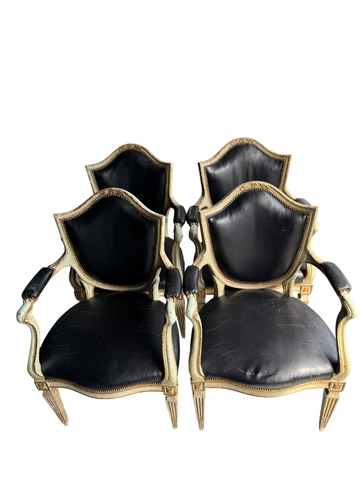 Two French Louis XVI style fauteuil armchairs with painted cream frames, black leather upholstery, nailhead trim, viewed from front