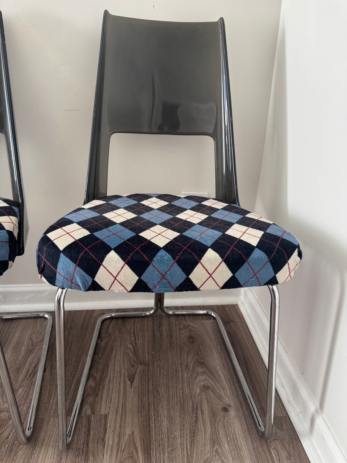 Close-up side view of single chair with high-backed smoked acrylic design and argyle patterned seat cushion