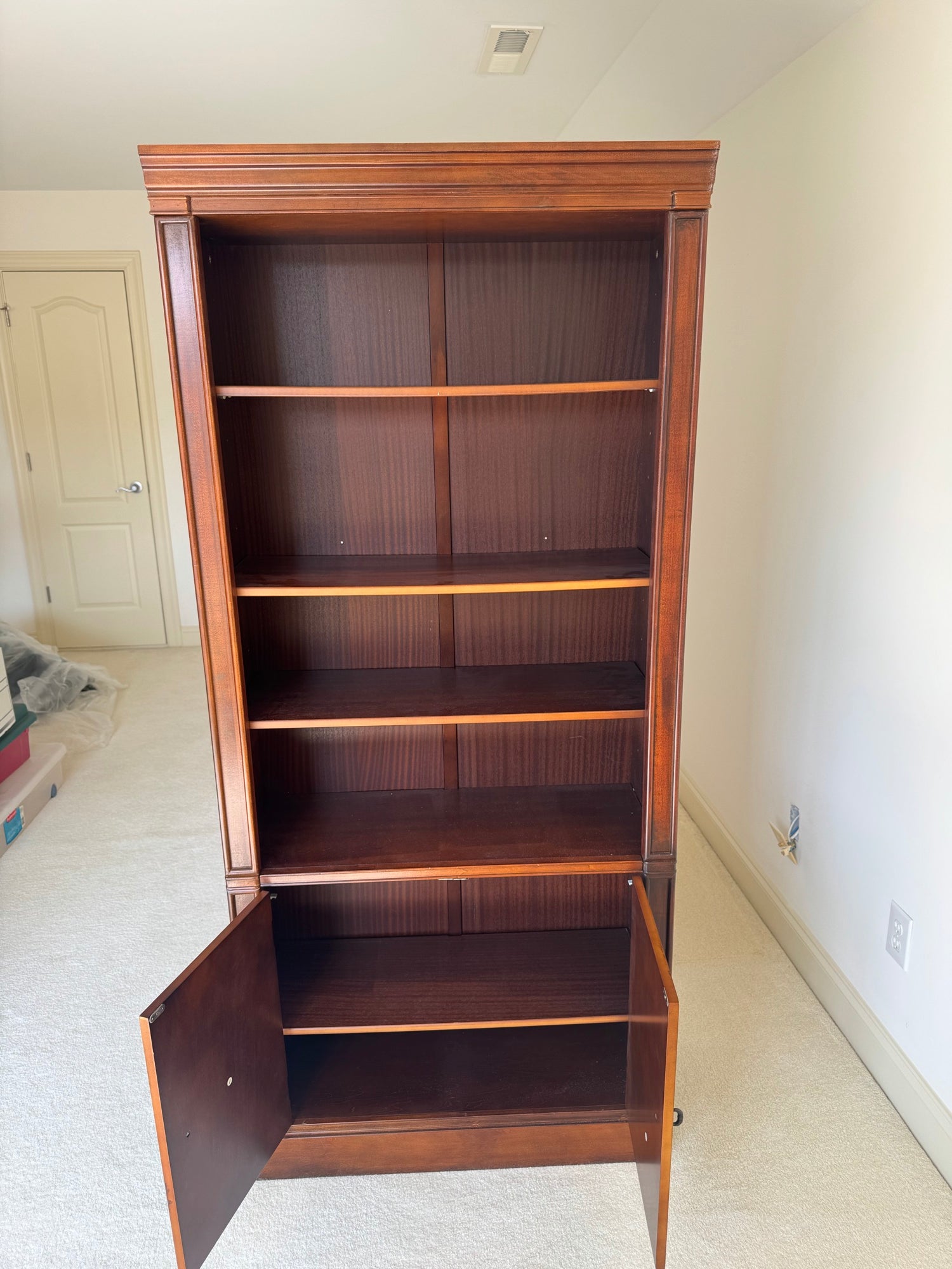 Same mahogany bookcase with one cabinet door open, revealing interior shelf storage space
