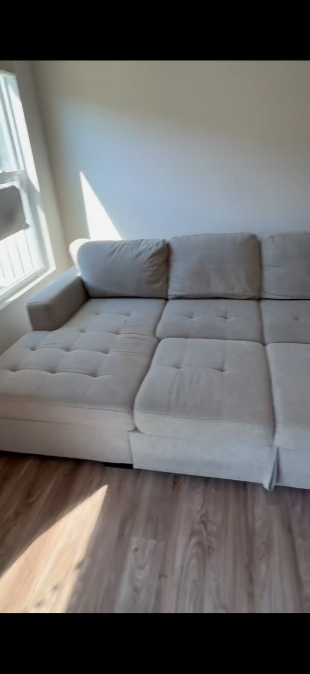 Gray tufted sectional sofa with chaise lounge, angled view showing seat cushions and arm details