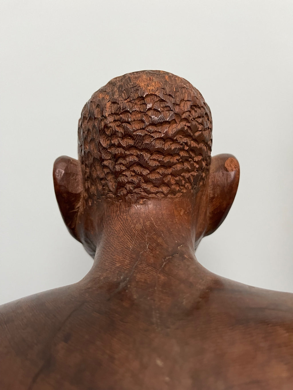 Back view of figure showing detailed hair carving with crosshatch pattern, rounded head