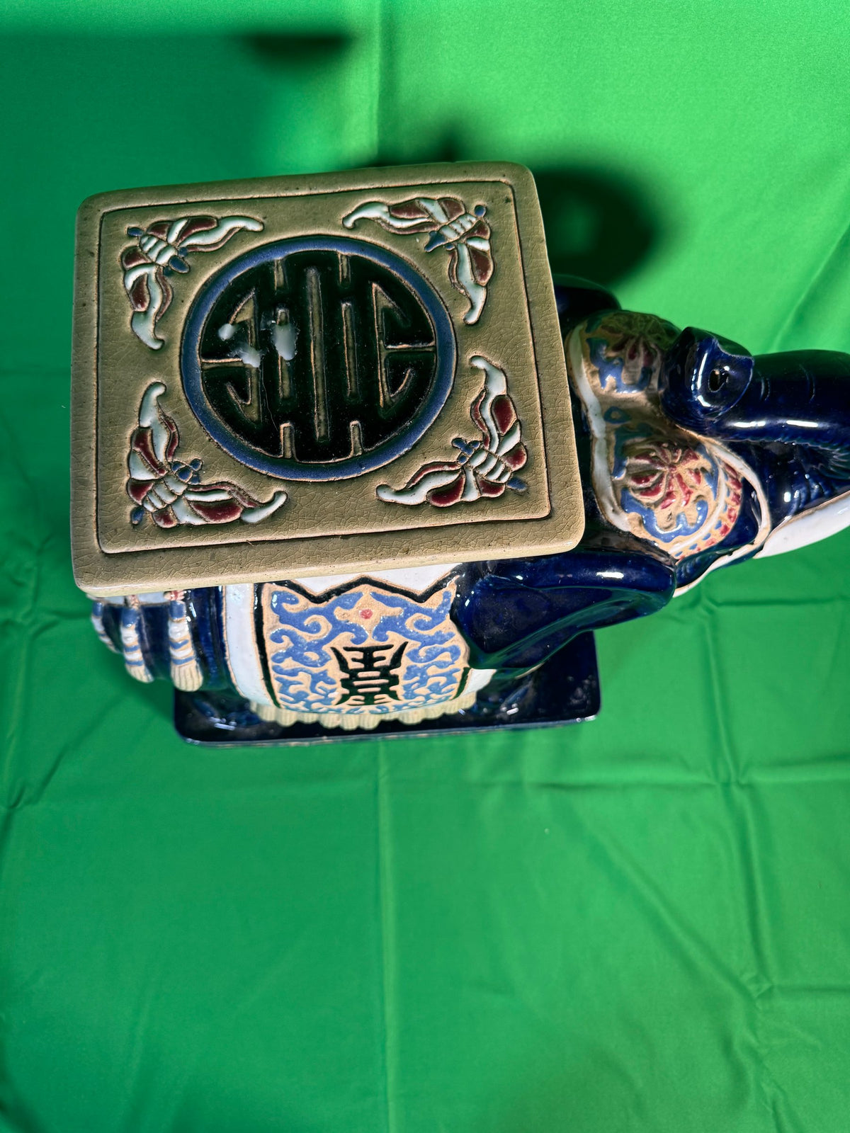 Large central cobalt blue ceramic elephant with gilt saddle cloth, flanked by two smaller cream and gold elephant stools on black base