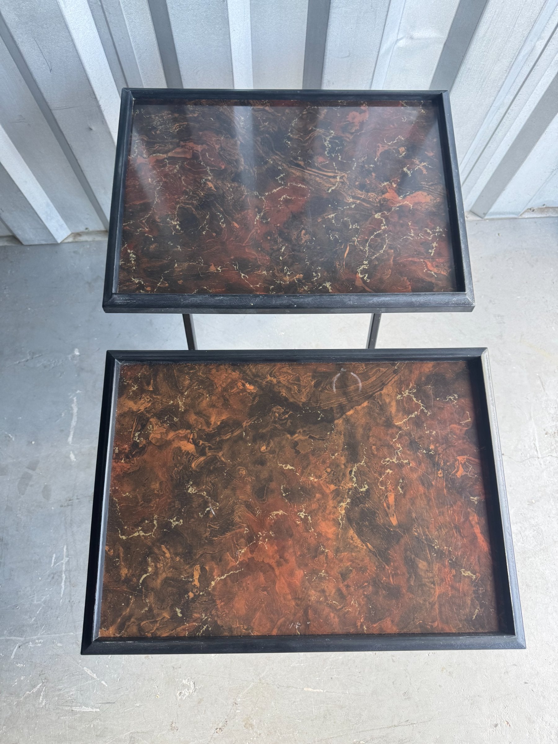 Close-up of two detached faux tortoiseshell tops displaying brown, amber and gold marbled pattern with black metal frames