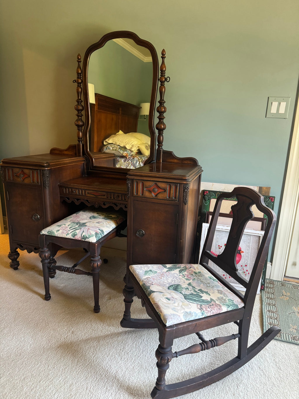 Vanity from side angle showing ornate carved details, turned finials, and floral upholstered bench