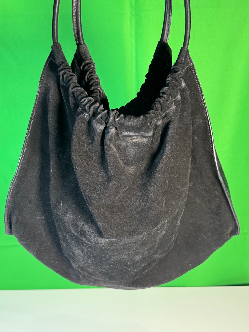 Bag interior view showing charcoal fabric lining and gathered top construction, green background