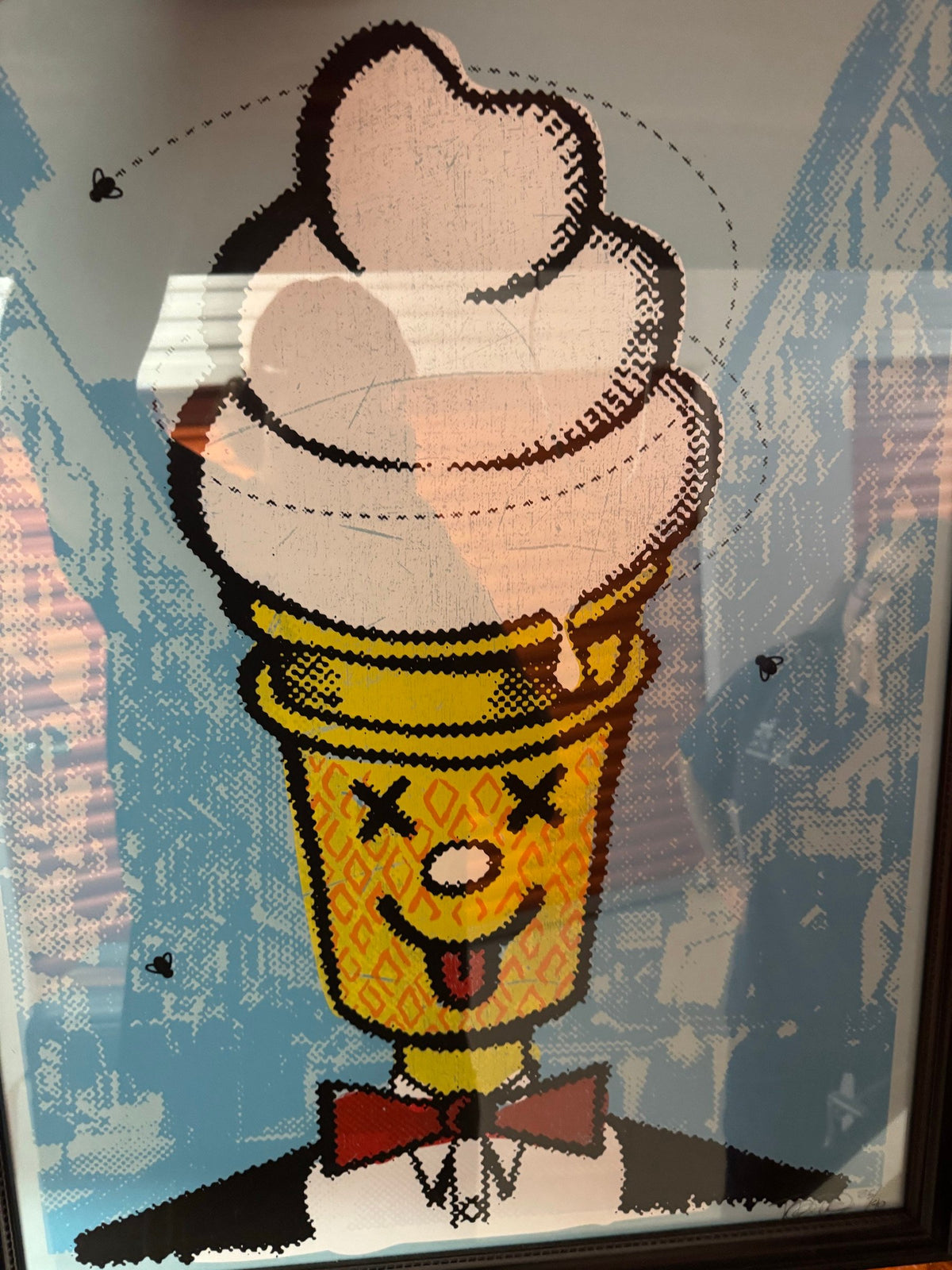 Framed ice-cream cone character screenprint on a city street in a dark wood frame