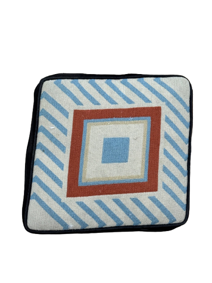 Vintage needlepoint pillow cover displayed flat, showing geometric square design in blue, cream, rust and black with diagonal striped border
