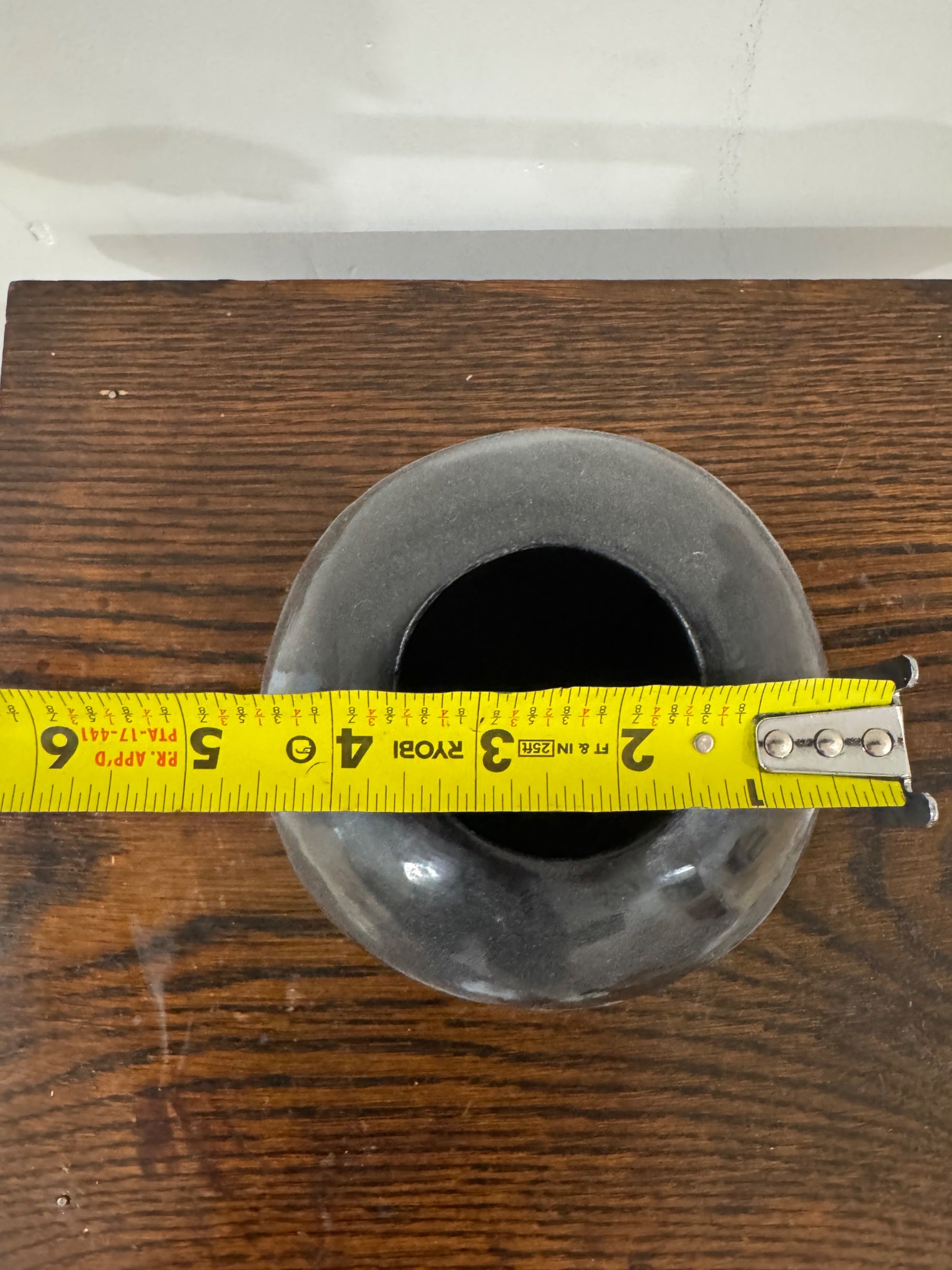 Overhead view of vase opening with measuring tape across diameter, demonstrating scale and circular rim opening of handmade ceramic vessel