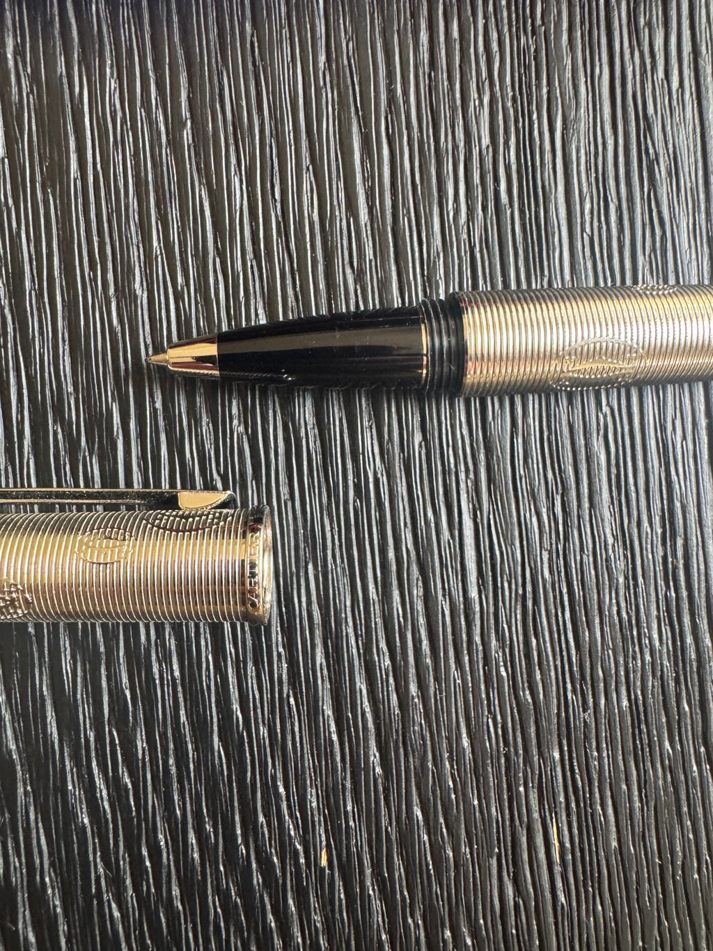 Close-up of pen barrel showing fine spiral ribbing and textured metal finish in warm metallic tone