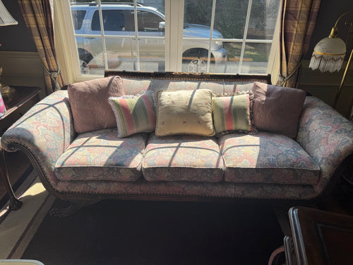 Full front view of floral damask sofa with rolled arms, three cushions, decorative pillows, and ornate wooden frame in bright natural light