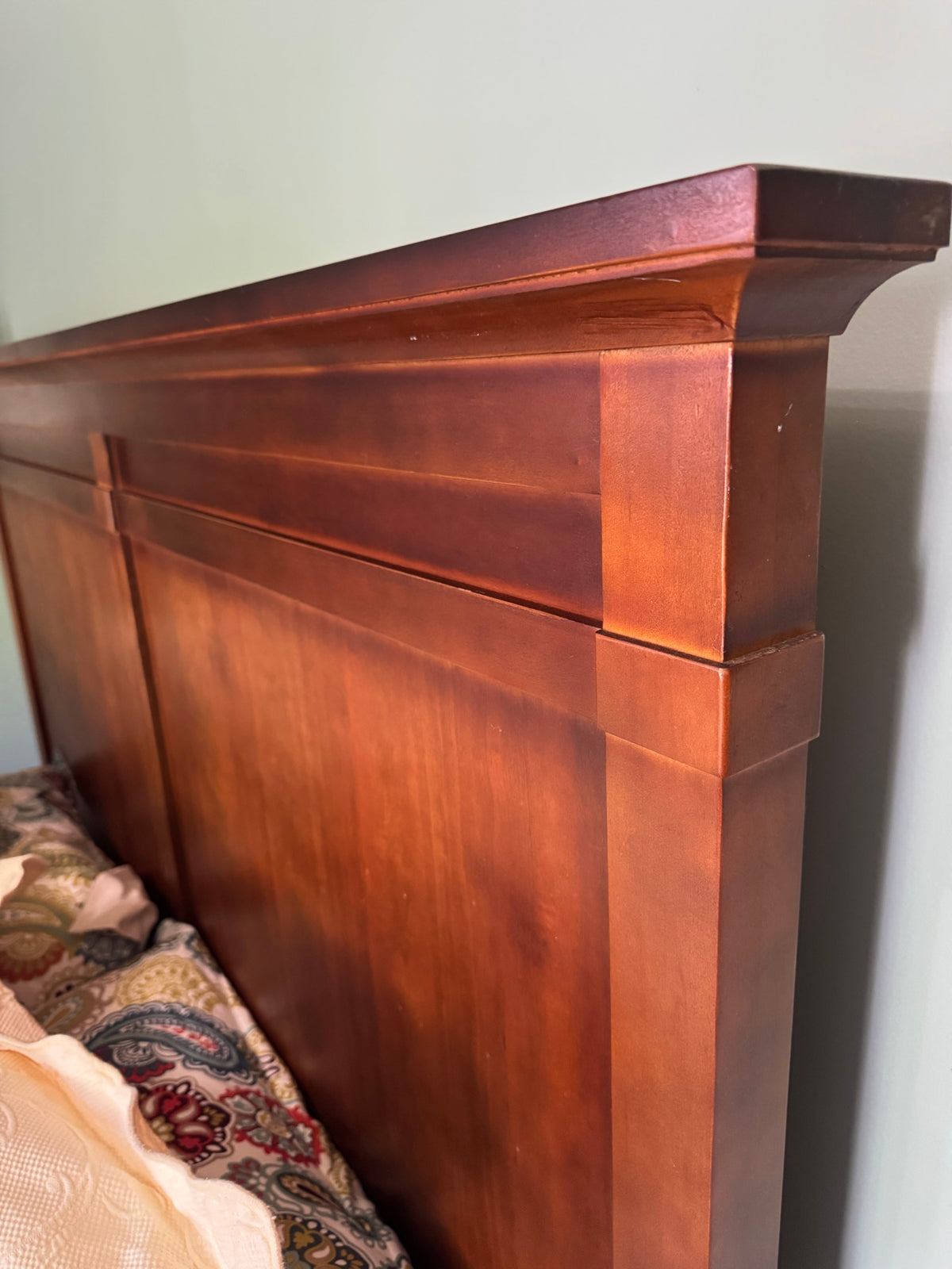 Close-up of cherry wood headboard side panel showing grain, finish, and stepped architectural detail