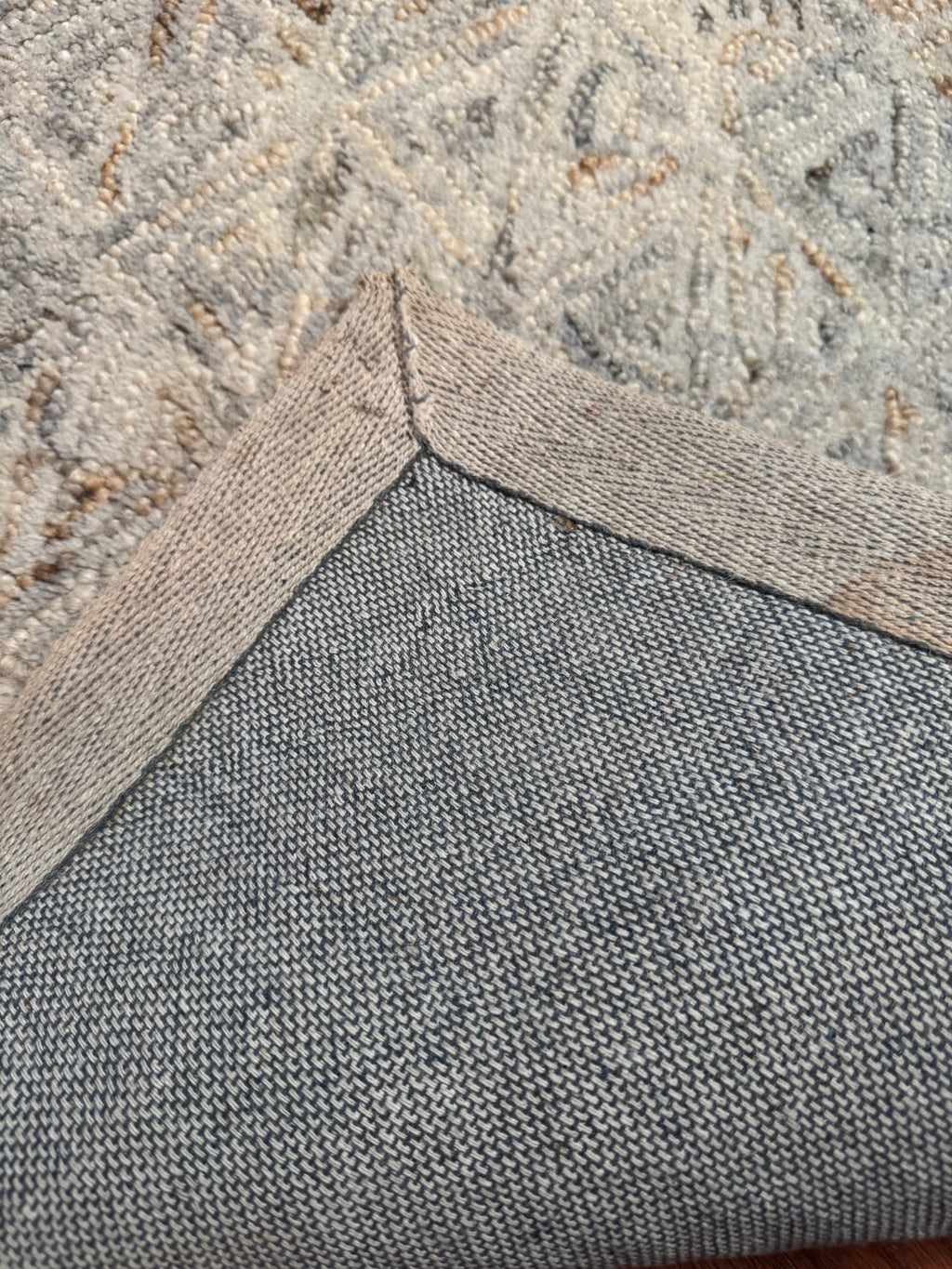 Close-up of the rug's woven backing and edge binding at the folded corner