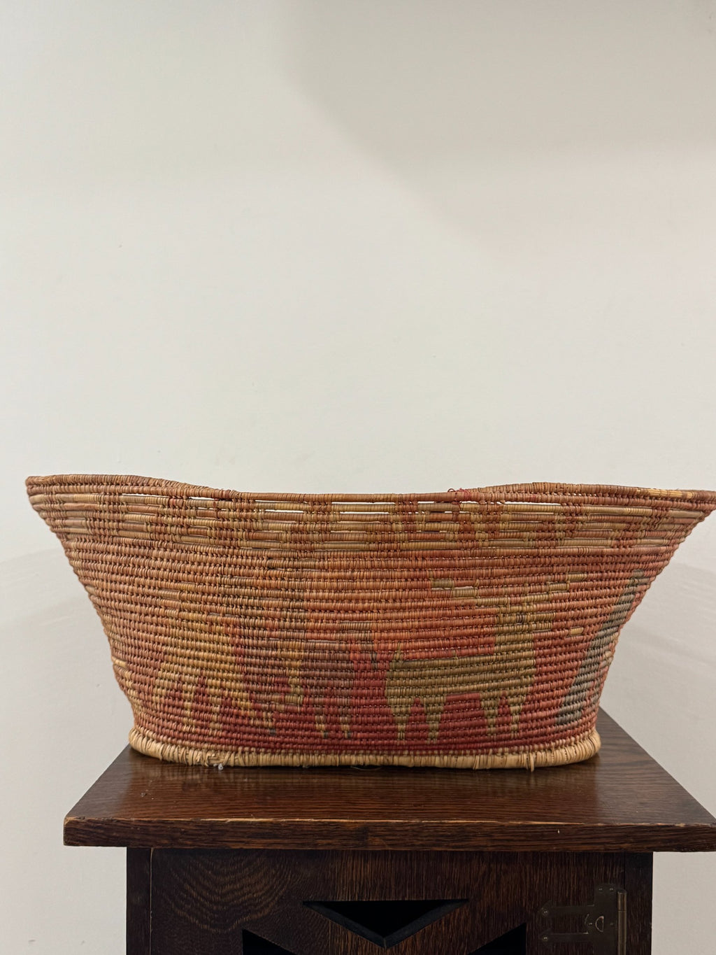 Bottom angle of basket showing tapered base and wrapped fiber rim detail on dark wood surface