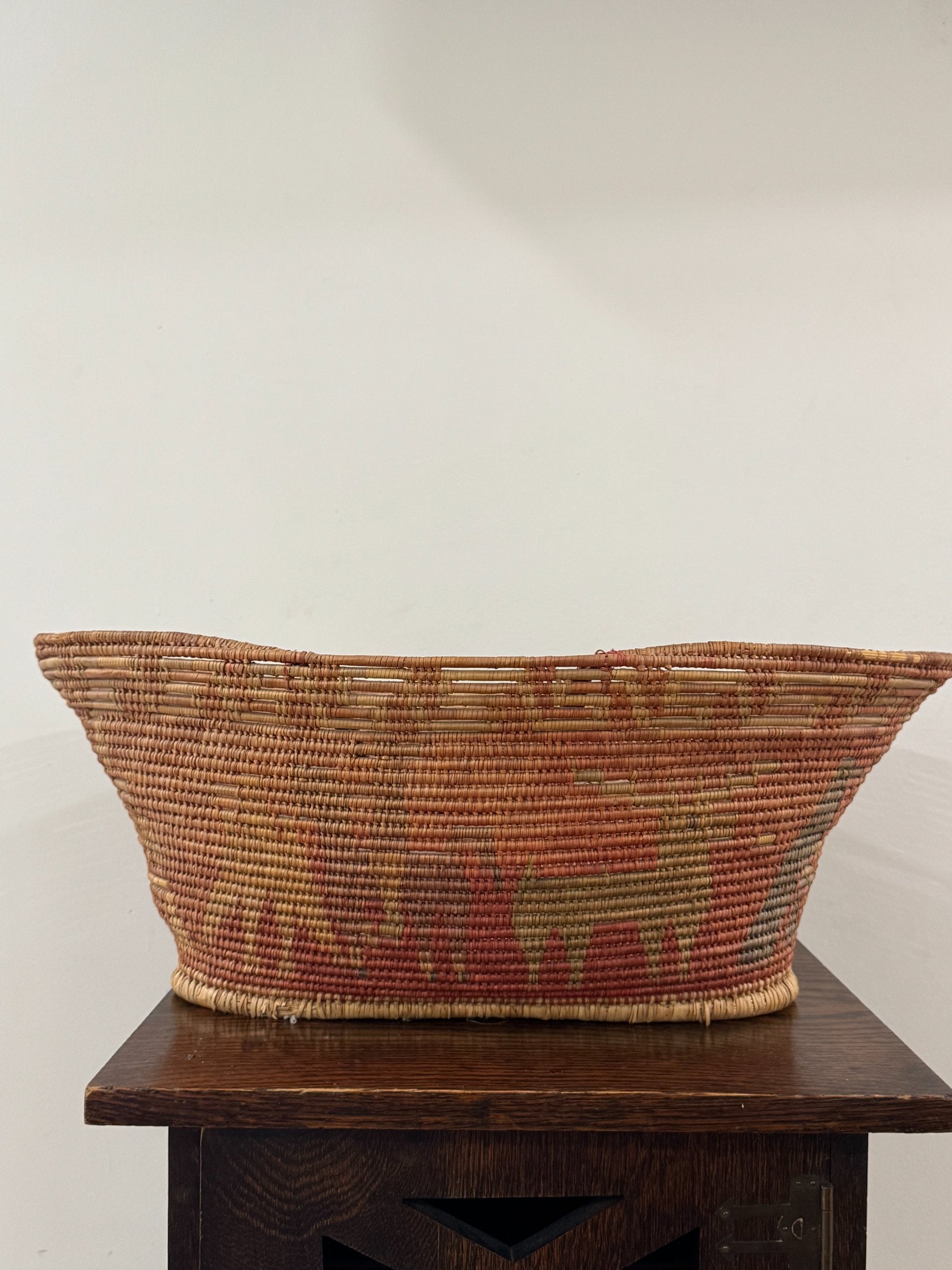 Bottom angle of basket showing tapered base and wrapped fiber rim detail on dark wood surface