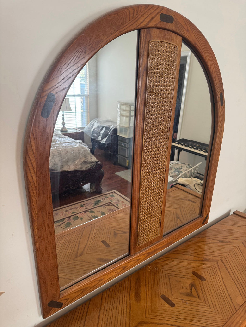 Arched oak mirror seen at an angle above the dresser