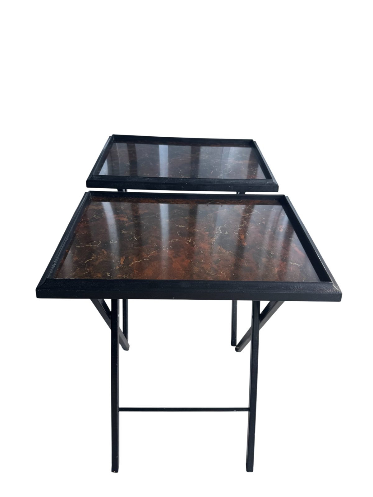 Pair of black metal nesting tables with faux tortoiseshell tops, viewed from front at angle showing both tables stacked
