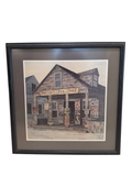 Framed pen and ink watercolour print of Johnson's Drug Store, a weathered wooden country store with signage, dormers and porch, signed by Barbara Hodgeman
