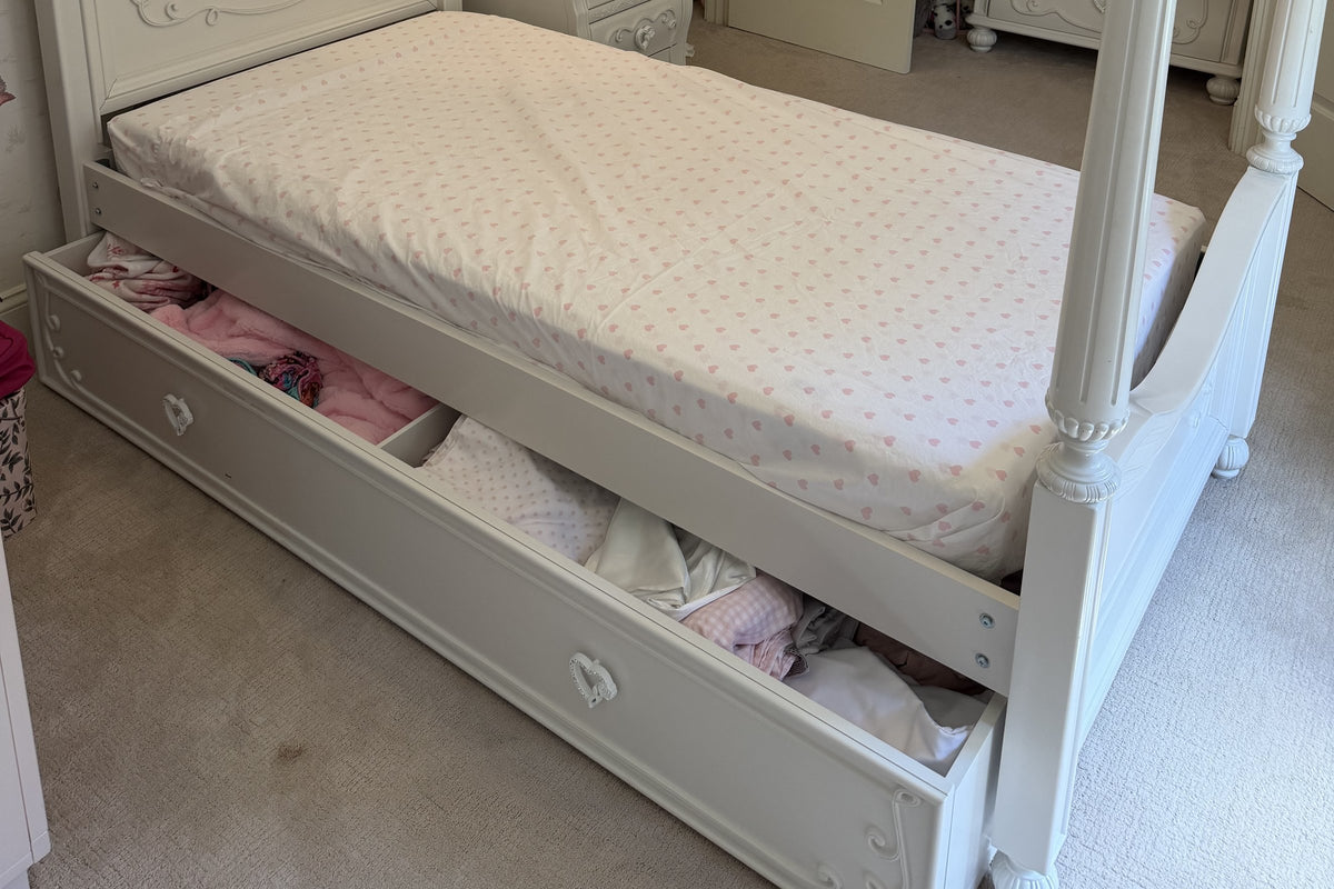 Storage trundle pulled out under the Sparkle White canopy bed