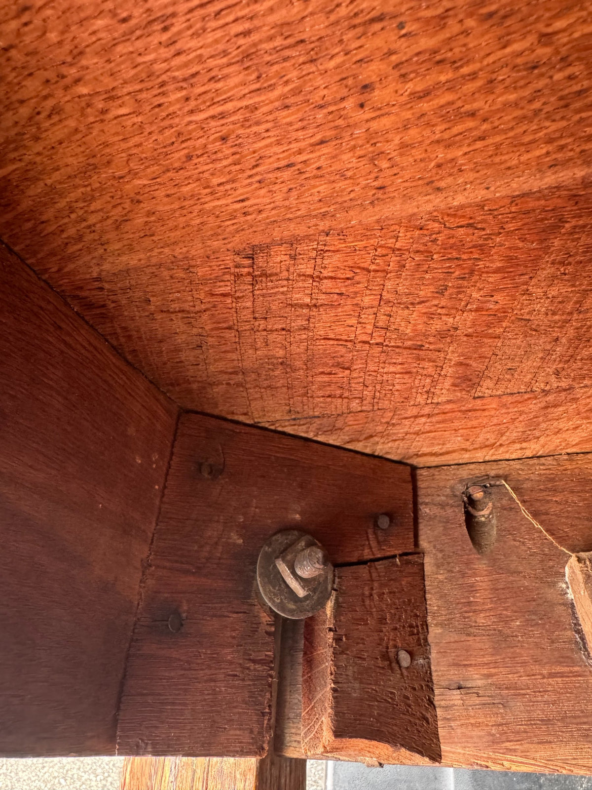 Detail of table corner showing mortise and tenon joinery, decorative wood grain pattern, and finish condition