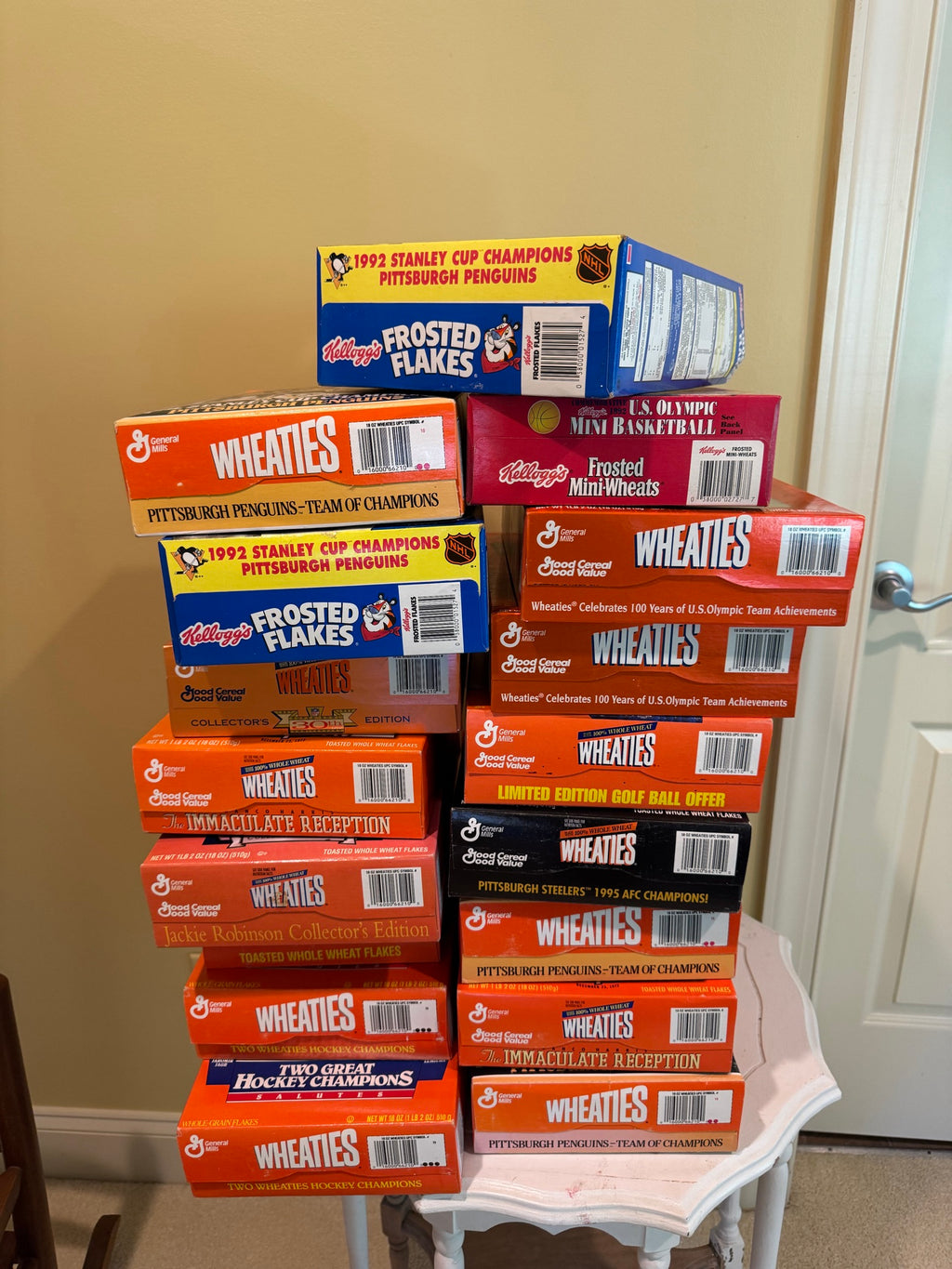 Stack of seventeen unopened cereal boxes featuring Wheaties and Frosted Flakes brands, displaying Pittsburgh sports championship themes on white table
