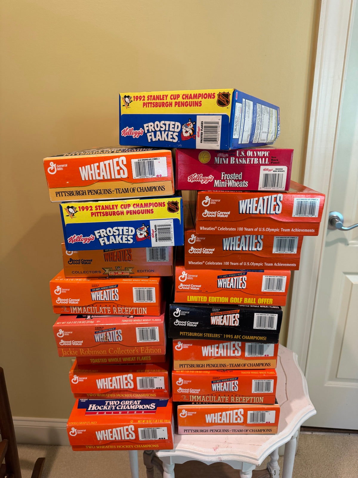 Stack of seventeen unopened cereal boxes featuring Wheaties and Frosted Flakes brands, displaying Pittsburgh sports championship themes on white table