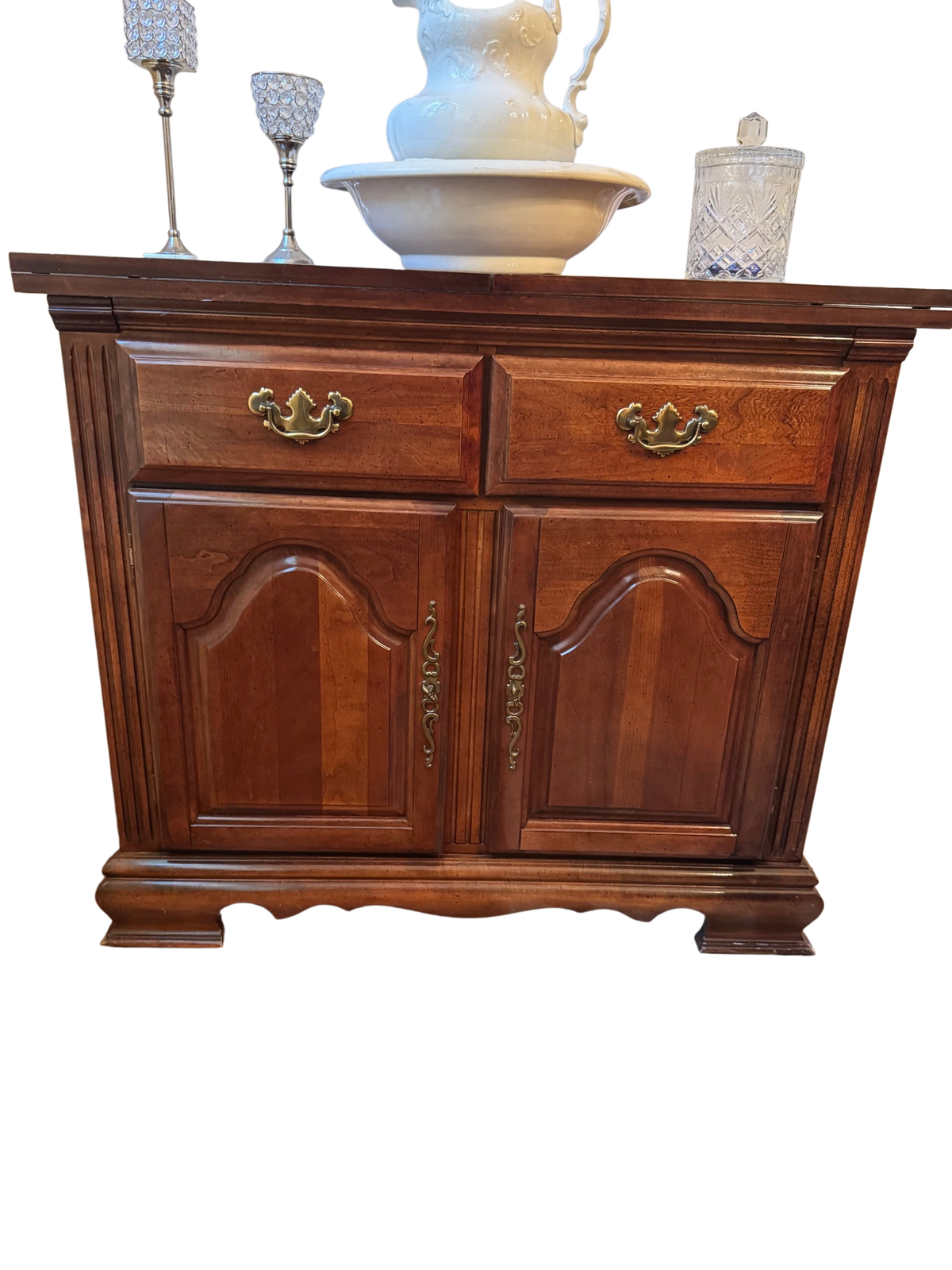 Cherry wood server buffet with two drawers and two arched-panel cabinet doors, brass hardware, shown with decorative items on top