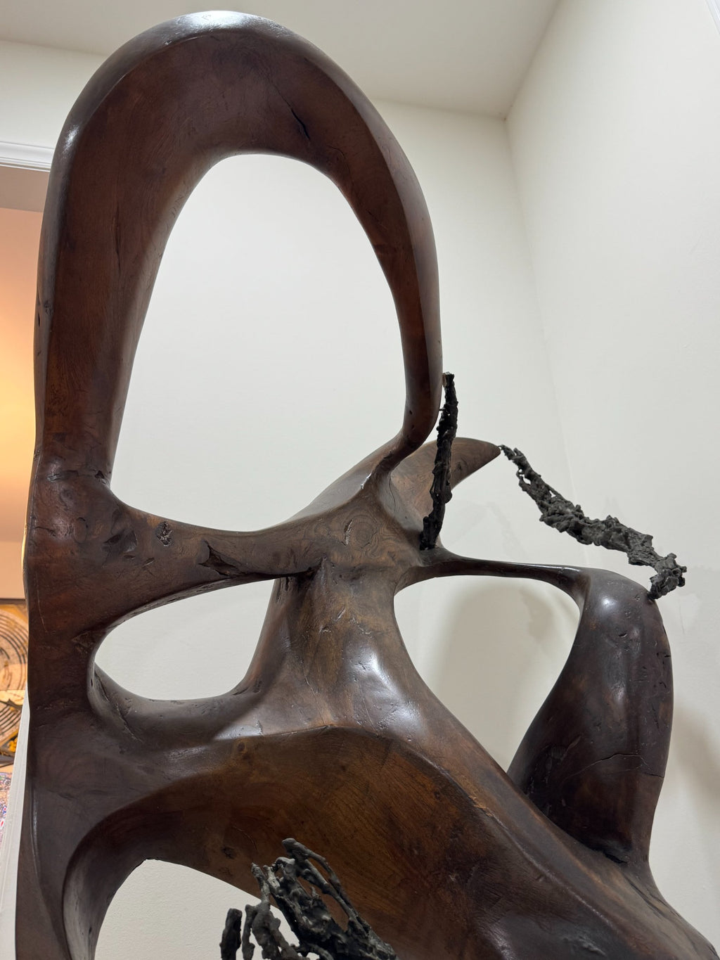 Close-up detail of upper carved section showing smooth curved forms, circular openings, and textured dark material accent, side angle