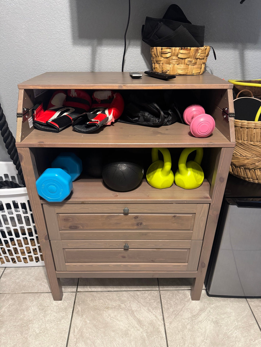 Home gym gear on a wooden cabinet with battle ropes hanging beside it