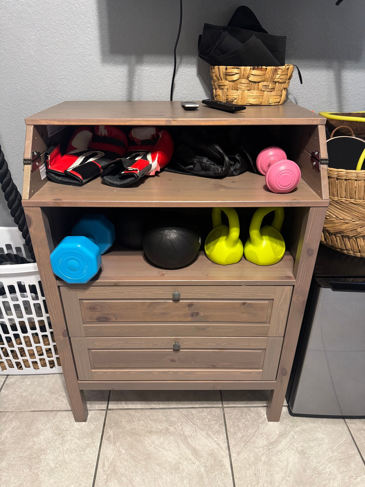 Home gym gear on a wooden cabinet with battle ropes hanging beside it