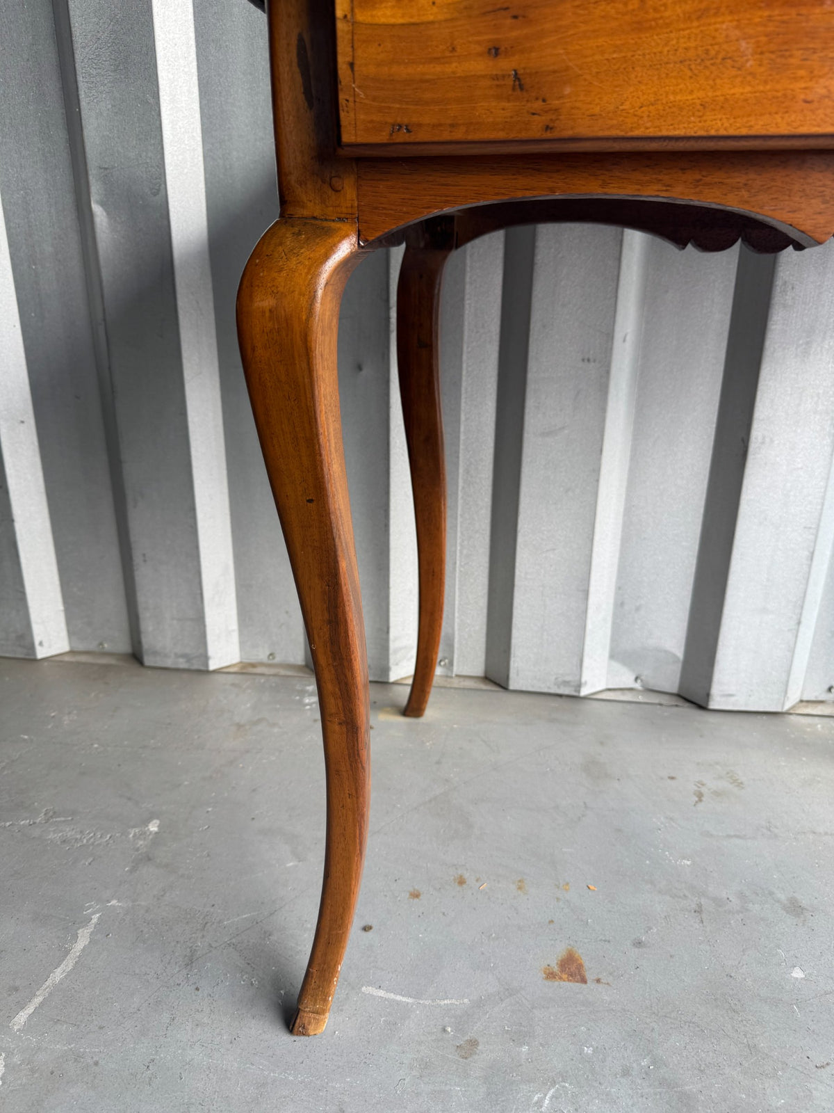Close-up of curved walnut cabriole leg with graceful bend and turned foot detail