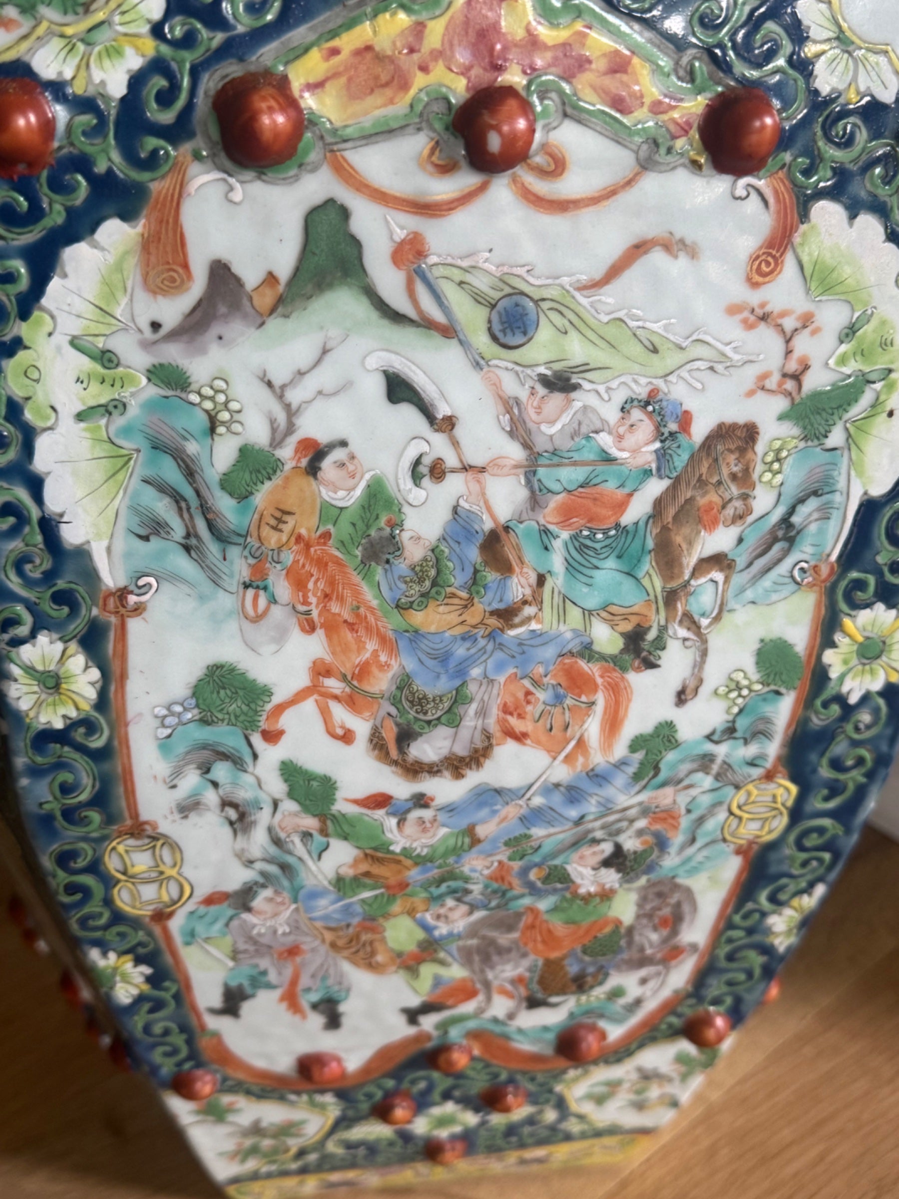 Close-up detail of central panel featuring painted figures, horses, trees, red spheres and ornamental dark blue scrollwork borders