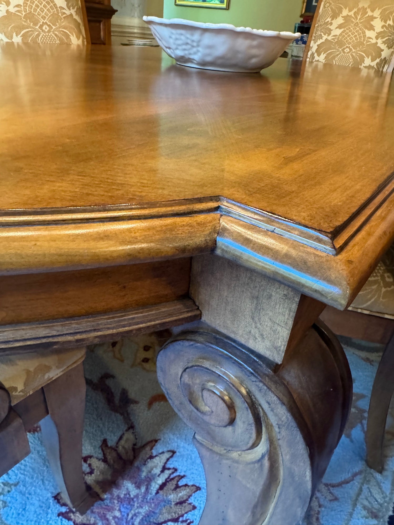 Table edge detail showing curved border trim, carved wooden pedestal base with spiral decoration