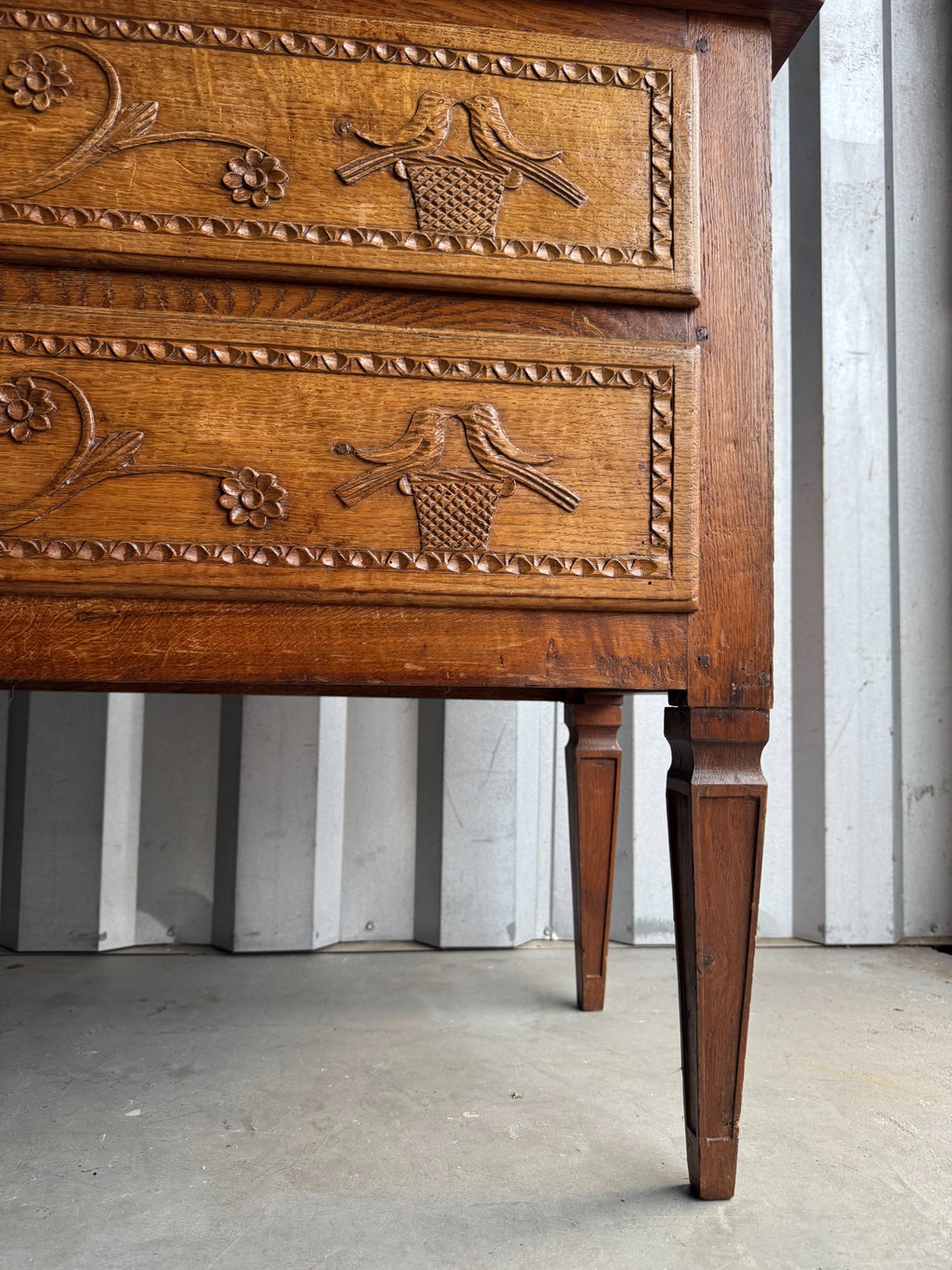 Close-up of lower drawer carving showing birds, flowers, and decorative details