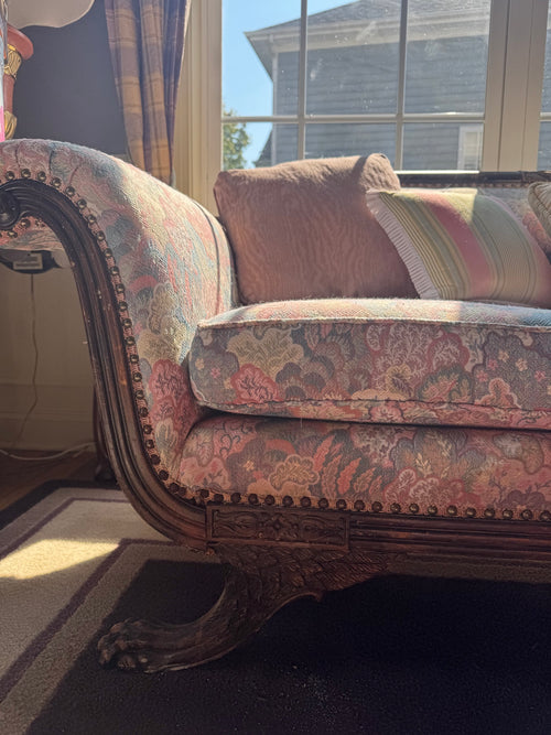 Close-up detail of left arm showing carved wooden frame, damask fabric in red and cream tones, and decorative nailhead trim