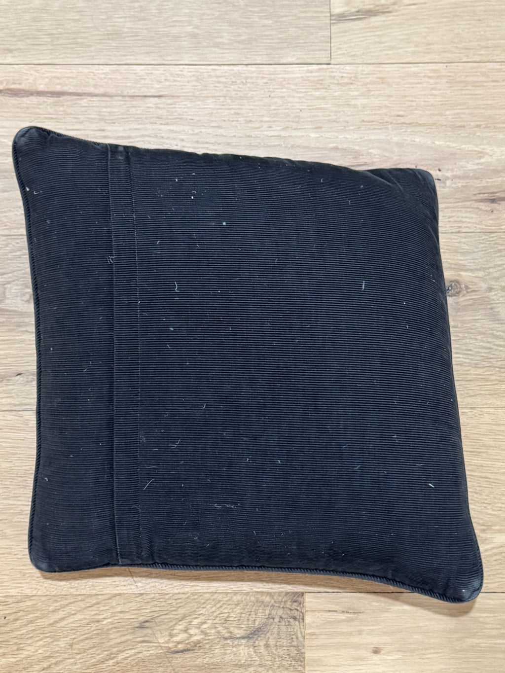 Dark navy corduroy pillow back showing fabric texture and wear from use