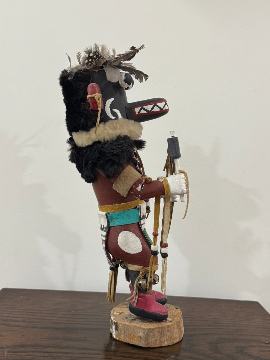 Side profile showing carved head with white spiral designs, red ears, black fur, and colorful body details